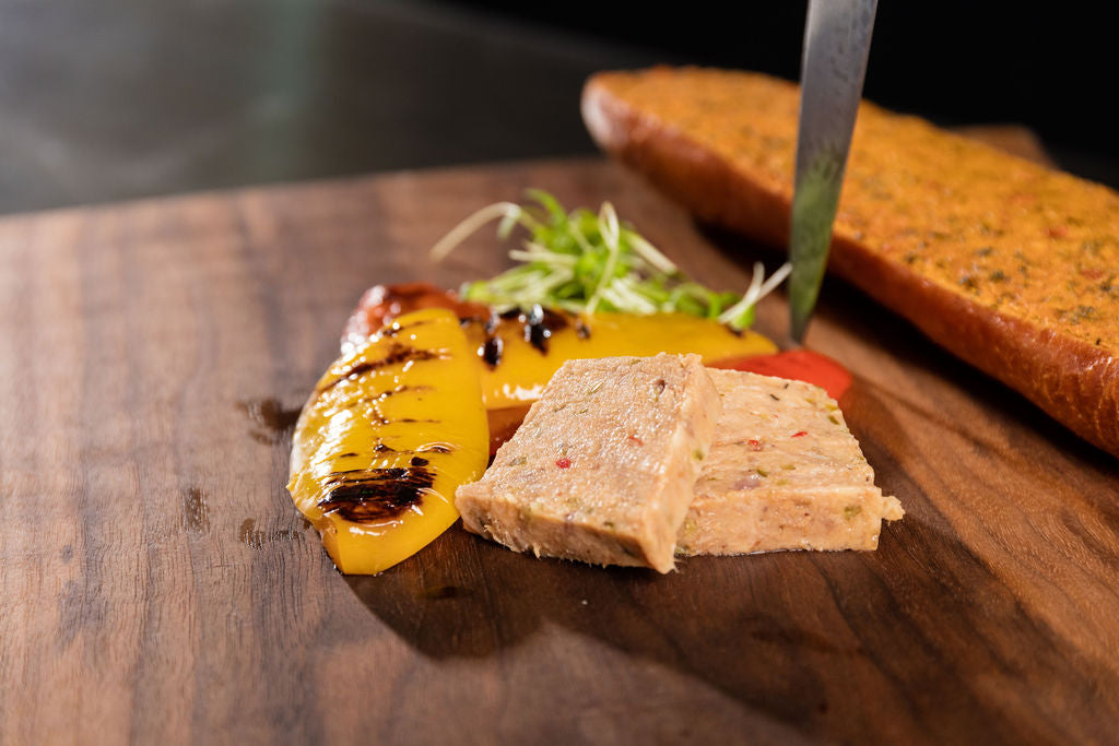Kalbfleisch-Terrine von Degusta Manufaktur auf Holzbrett mit grilliertem Peperoni und Balsamico