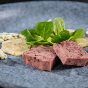 Wild-Terrine von Degusta Manufaktur, Scheiben mit Nüsslisalat auf blauem Teller